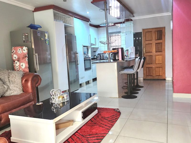 Open-plan living and kitchen area featuring tiled flooring, a central kitchen island, and built-in cabinetry, creating a functional combined living space.