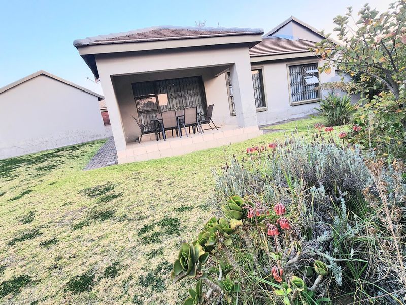 Rear view of the townhouse featuring a covered tiled patio, security gates, and a private garden area with a paved walkway.
