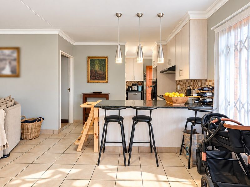 Open-plan living and kitchen area featuring a central island with granite countertops, modern pendant lighting, and tiled flooring throughout.