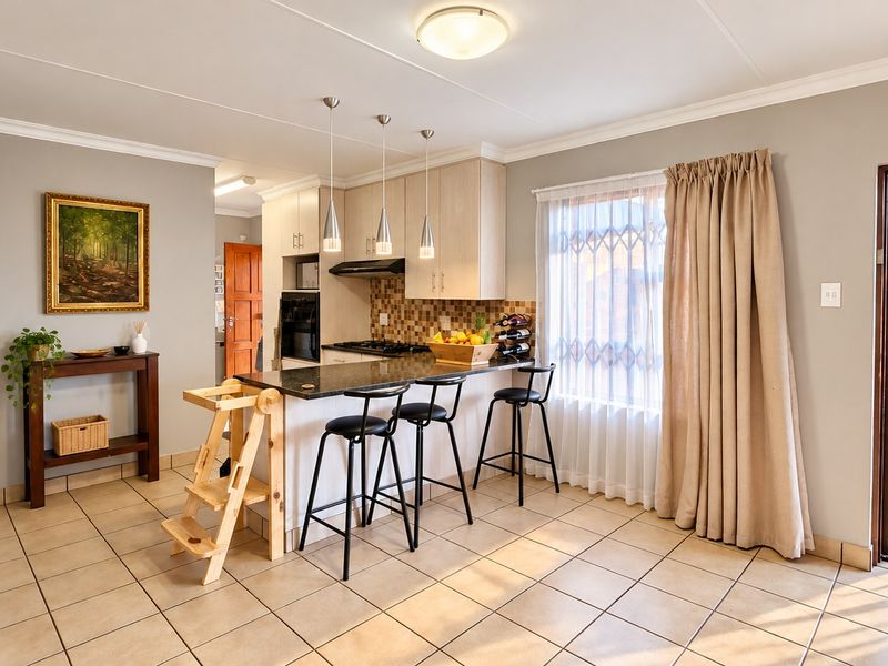 Open-plan kitchen and living area featuring tiled floors, granite countertops, built-in appliances, and direct access to an outdoor patio through a security gate.
