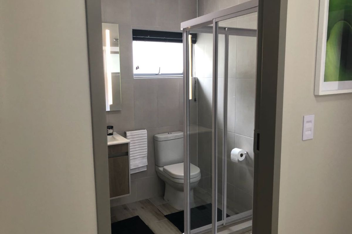 A modern, well-maintained bathroom featuring a glass shower enclosure, vanity cabinet, and neutral tiled finishes.