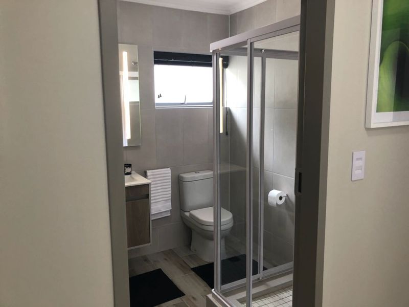 A modern, well-maintained bathroom featuring a glass shower enclosure, vanity cabinet, and neutral tiled finishes.