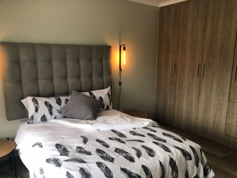 A well-maintained bedroom featuring modern built-in wooden cupboards and stylish wall-mounted accent lighting.