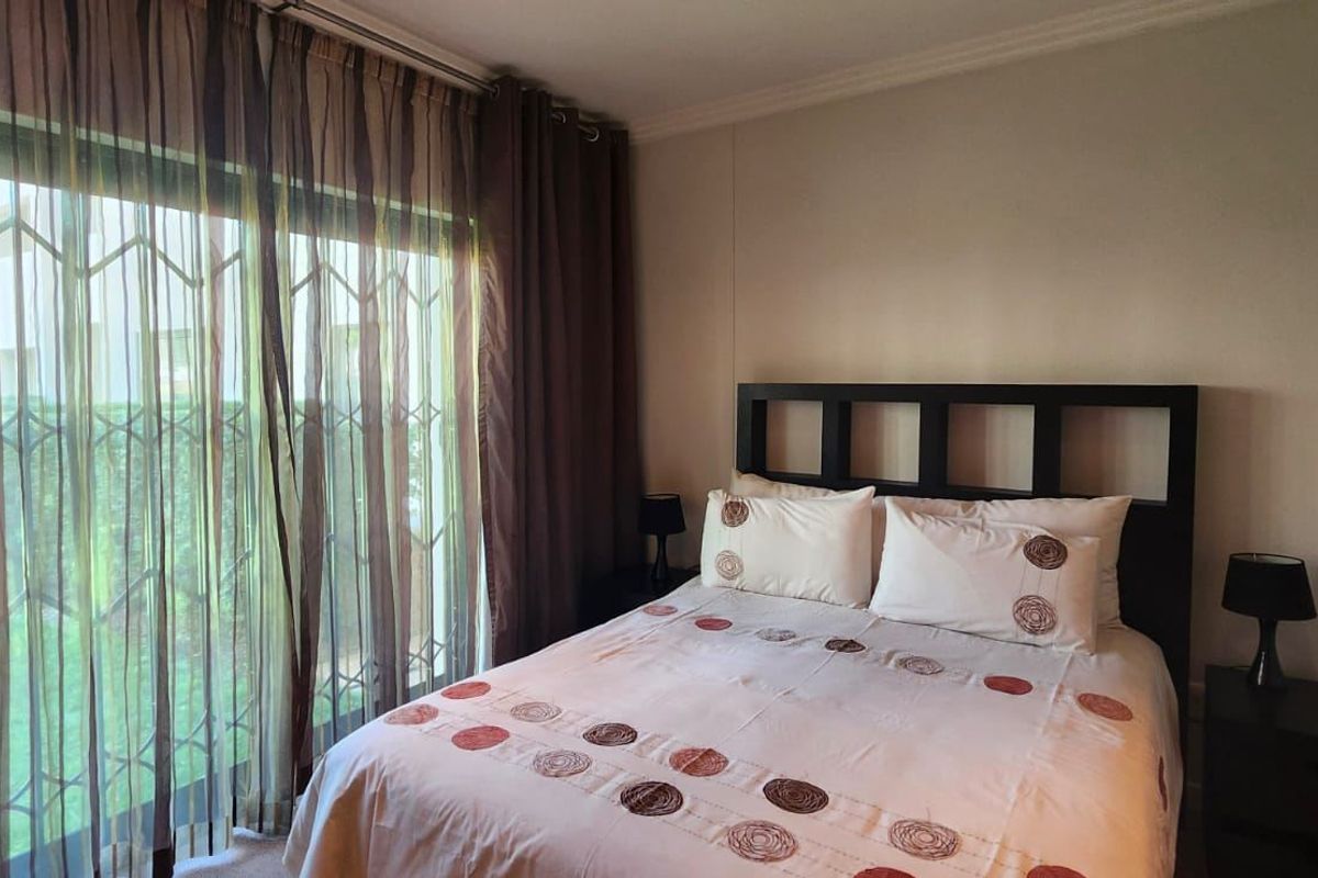 A bedroom featuring a sliding glass door with a security gate, providing access to the exterior and natural light.