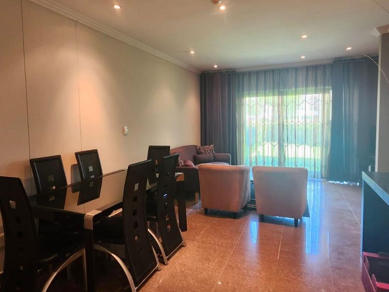 An open-plan living and dining area featuring polished tiled flooring, recessed downlighting, and a sliding glass door leading to the exterior.