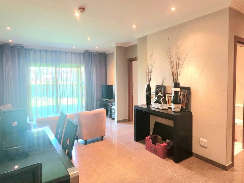 An open-plan living and dining area featuring tiled flooring, recessed downlighting, and a sliding glass door leading to the exterior.