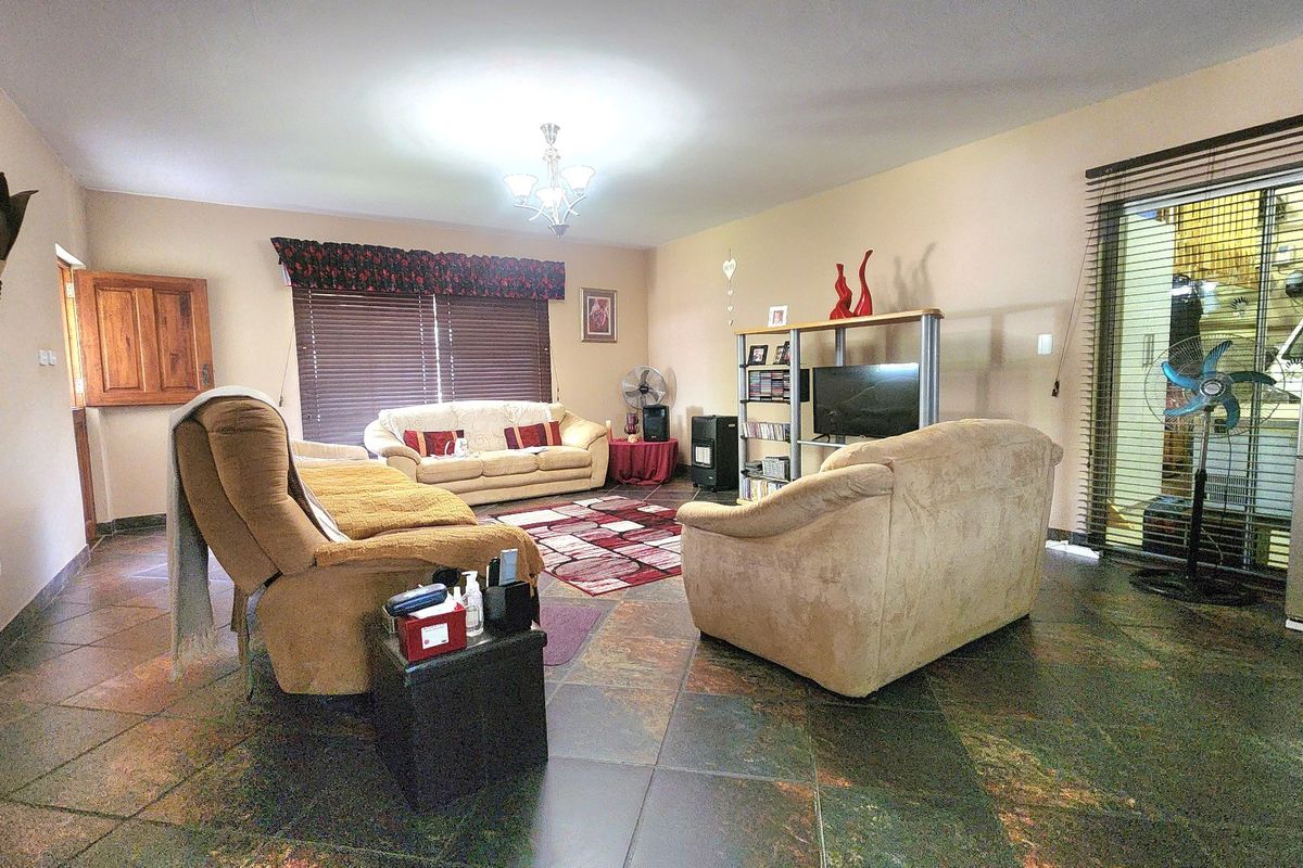Spacious living room featuring dark tiled flooring, large sliding glass doors with blinds, and neutral wall finishes.