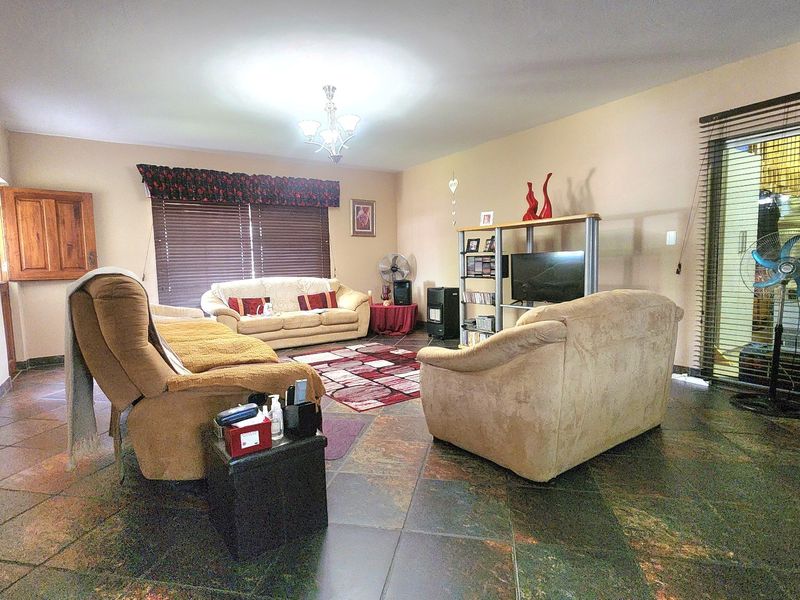Spacious living room featuring dark tiled flooring, large sliding glass doors with blinds, and neutral wall finishes.
