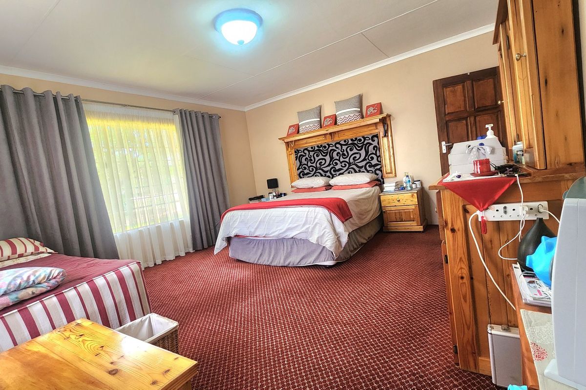 Spacious bedroom featuring fitted wooden cabinetry, a built-in headboard, and carpeted flooring, offering a functional layout with ample space.