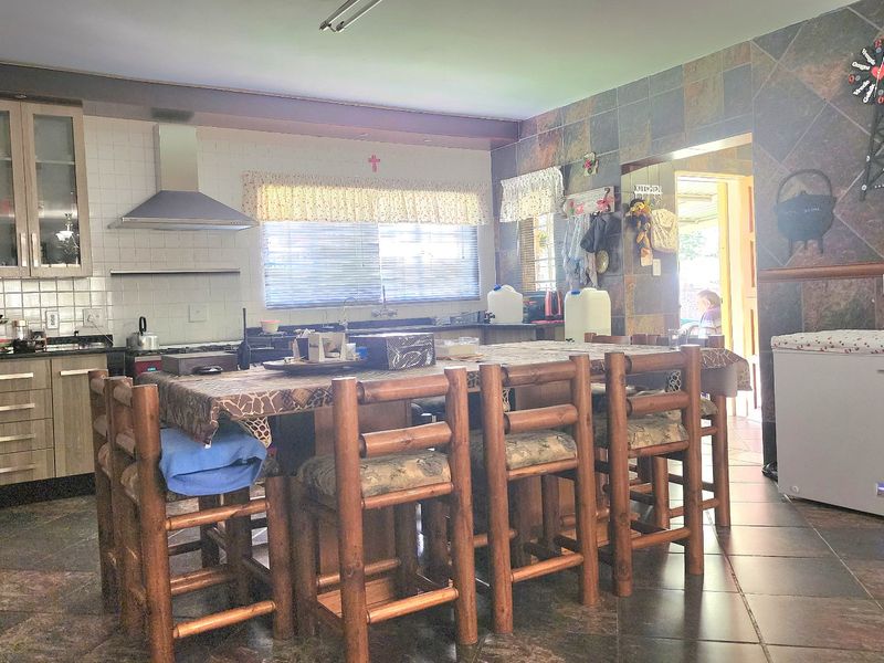 Open plan kitchen and dining area featuring tiled flooring, extensive wall tiling, and built-in cabinetry with a stainless steel extractor fan.