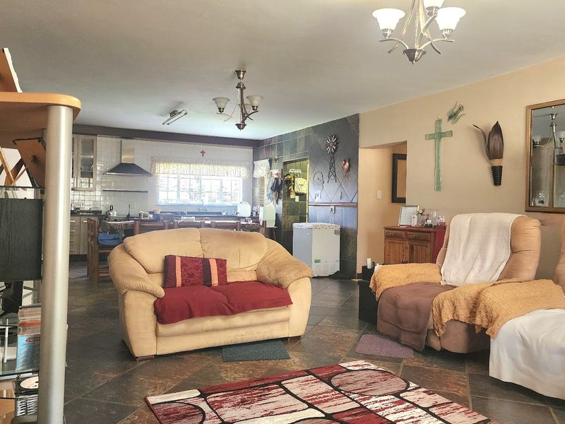 Open-plan living and kitchen area featuring tiled flooring, a tiled feature wall, and functional kitchen cabinetry with an integrated extractor fan.