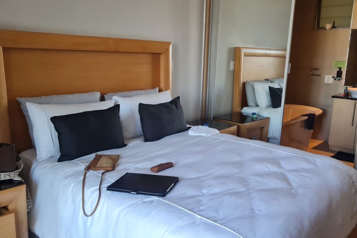 A well-maintained bedroom featuring a built-in wardrobe with mirrored sliding doors and an integrated en-suite bathroom.