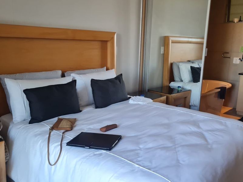 A well-maintained bedroom featuring a built-in wardrobe with mirrored sliding doors and an integrated en-suite bathroom.