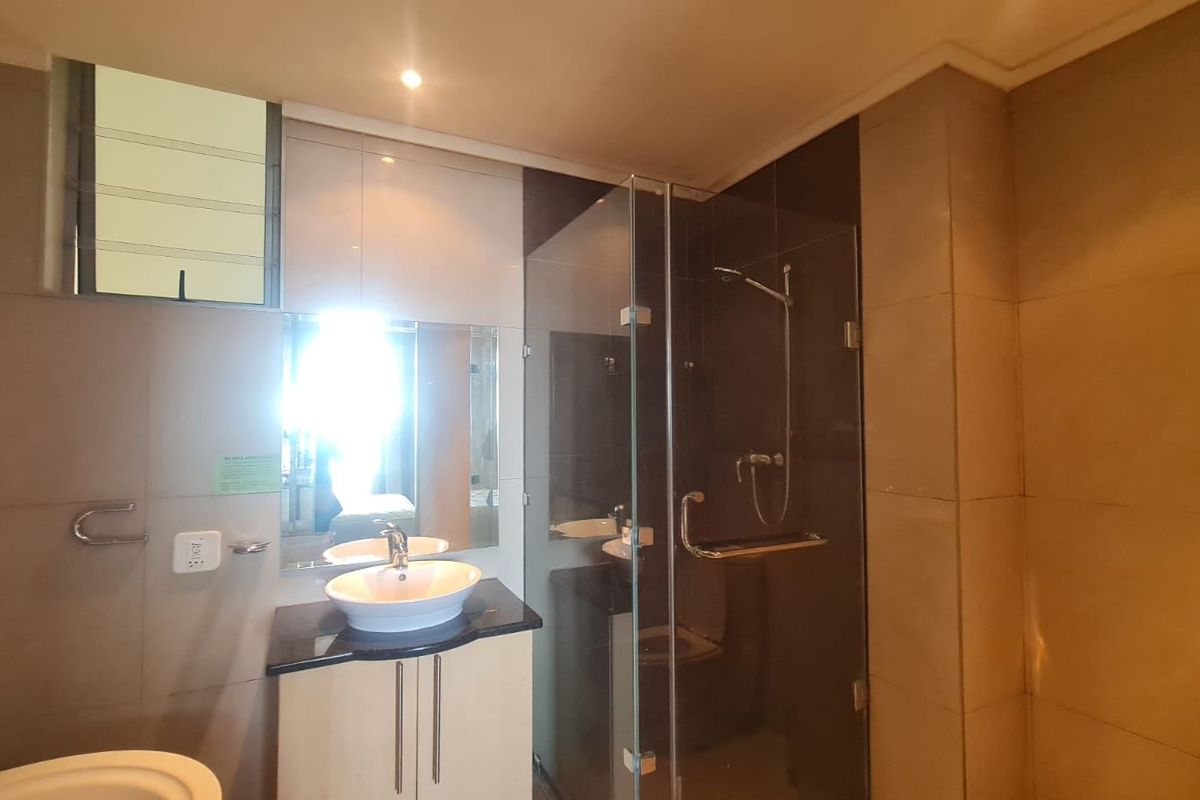Modern bathroom featuring a vessel sink vanity, glass-enclosed shower, and neutral wall tiling, offering a clean and functional space.