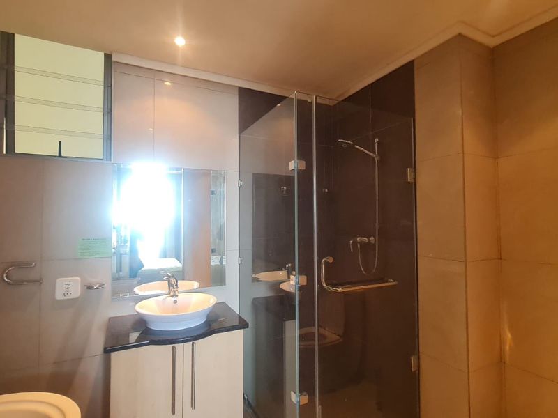 Modern bathroom featuring a vessel sink vanity, glass-enclosed shower, and neutral wall tiling, offering a clean and functional space.