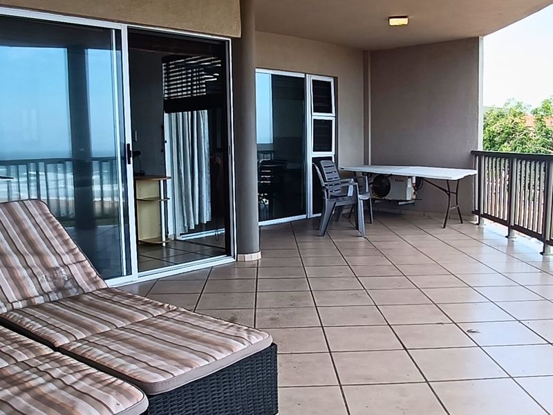 Spacious covered balcony featuring tiled flooring, metal balustrades, and large sliding glass doors providing seamless access to the interior living area.