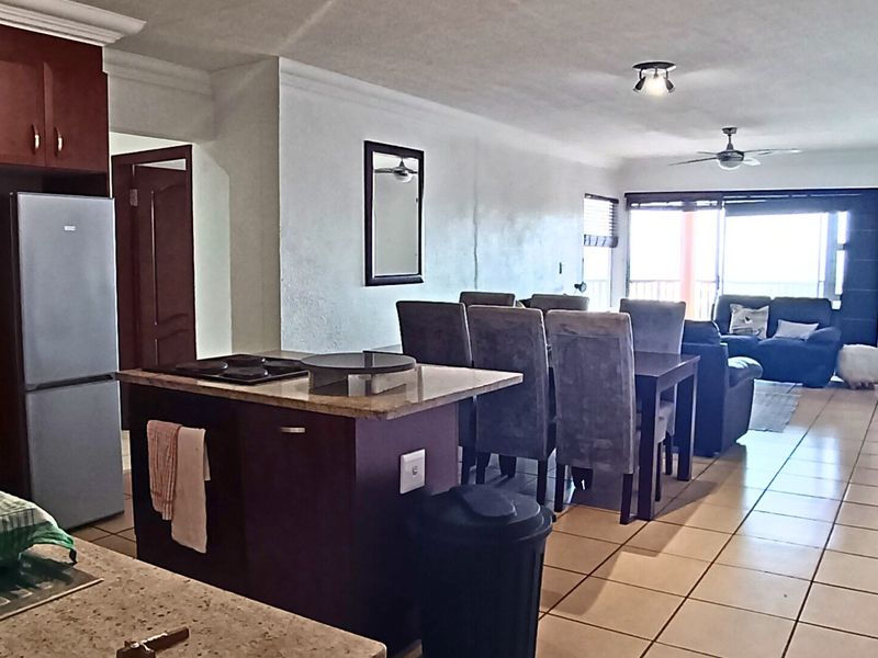 Open plan living and dining area featuring a functional kitchen with granite countertops, tiled flooring, and direct access to a balcony.