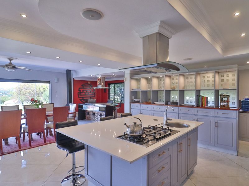 Spacious open-plan kitchen and dining area featuring a central island with gas hob, modern cabinetry, and recessed lighting, creating a bright, functional living space.