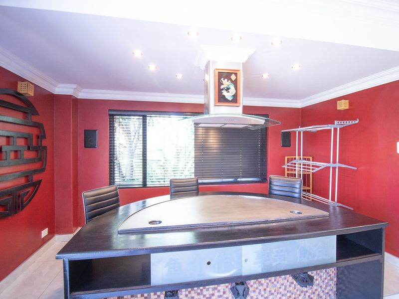 A unique kitchen space featuring a built-in teppanyaki grill with a stainless steel extractor hood, recessed lighting, and bold red wall finishes.