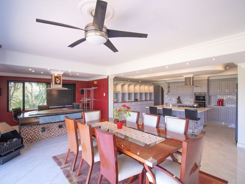 Spacious open-plan living and dining area featuring a modern kitchen with island, built-in appliances, tiled floors, and a cozy freestanding fireplace.