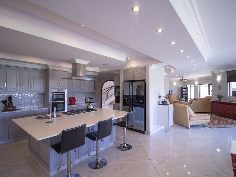Spacious open-plan kitchen and living area featuring a modern kitchen island, high-end built-in appliances, sleek cabinetry, and polished tiled flooring throughout.