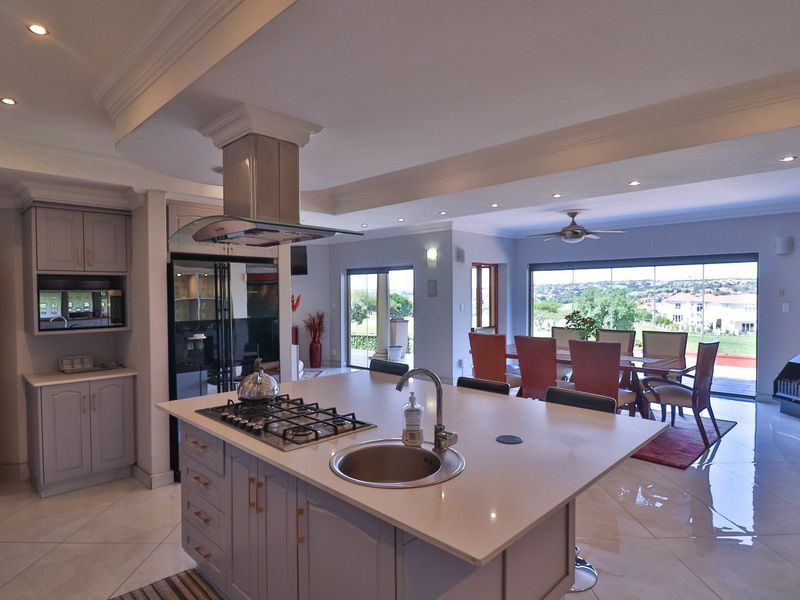 Spacious open-plan kitchen and dining area featuring a central island with gas hob, modern cabinetry, fireplace, and large sliding doors leading to the outdoors.