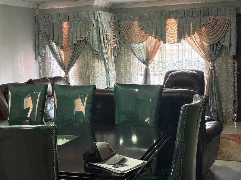 A living room area featuring decorative ceiling cornices and security bars on the windows, providing a functional space with traditional window treatments.