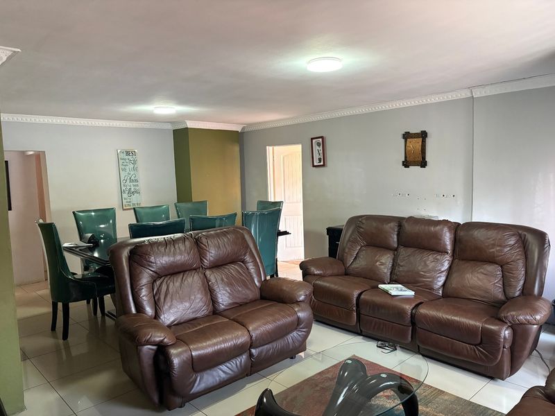 An open-plan living and dining area featuring tiled flooring, ceiling cornices, and neutral wall finishes, providing a functional space for family living.