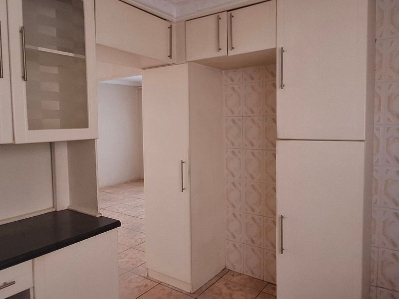 A functional kitchen space featuring built-in cabinetry, tiled backsplash, and tiled flooring, offering a clean canvas for potential updates.