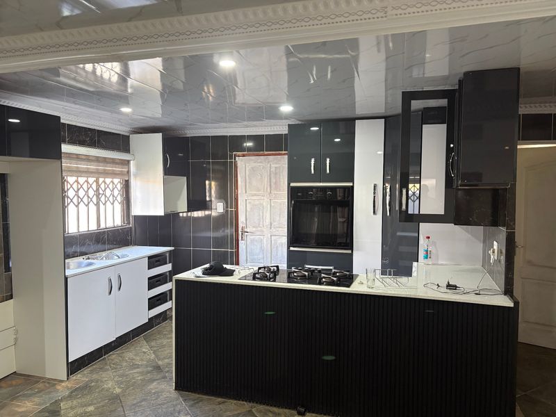 Modern kitchen featuring high-gloss cabinetry, integrated oven, gas hob, and tiled finishes, offering a contemporary layout with ample storage and workspace.