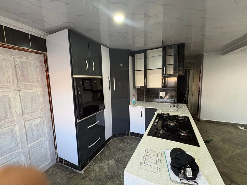 Modern kitchen featuring high-gloss cabinetry, built-in oven, gas hob, and stone countertops, offering a functional layout with contemporary finishes.