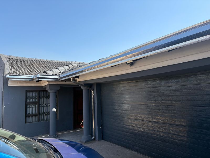 Front exterior view of the property featuring a dark-toned garage door, tiled roof, and decorative columns at the entrance.