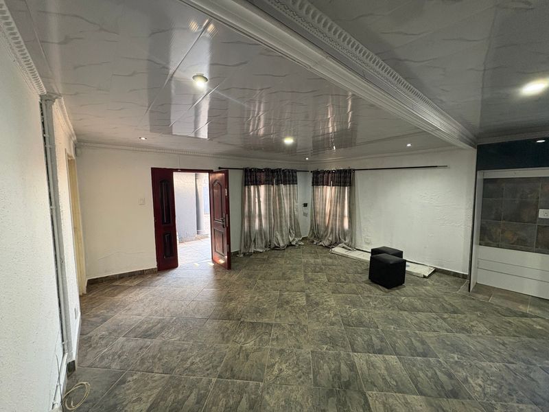 Spacious living area featuring large format floor tiles, recessed lighting, and decorative ceiling molding, providing a neutral canvas for interior design.