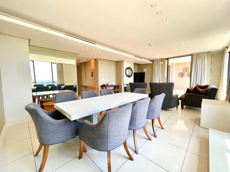 Spacious open-plan living and dining area featuring polished tiled flooring, recessed ceiling lighting, and large sliding glass doors leading to an outdoor space.