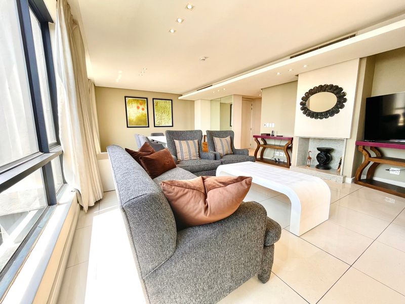 Spacious living room featuring large floor-to-ceiling windows, tiled flooring, recessed lighting, and a built-in fireplace, offering a bright and modern atmosphere.