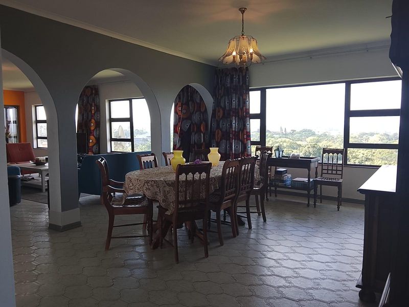 Spacious open-plan living and dining area featuring arched architectural details, large windows with natural light, and tiled flooring throughout.