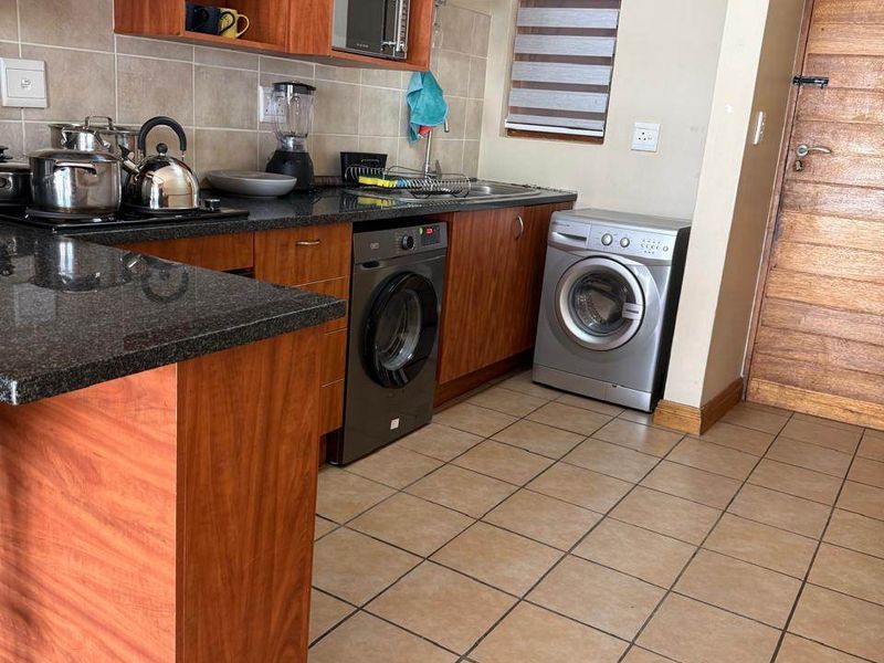 A functional kitchen featuring wooden cabinetry, granite countertops, tiled flooring, and a tiled backsplash, providing a practical workspace with integrated appliance connections.