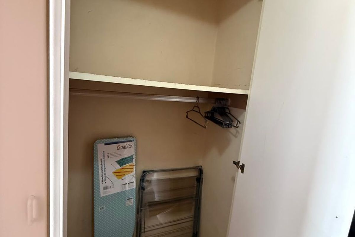A standard bedroom closet featuring a built-in storage shelf and a hanging rail, providing functional storage space.
