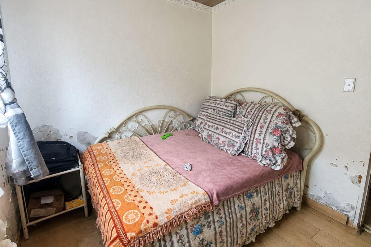 A bedroom featuring tiled flooring and crown molding, currently requiring wall repairs and cosmetic updates to improve the overall condition.