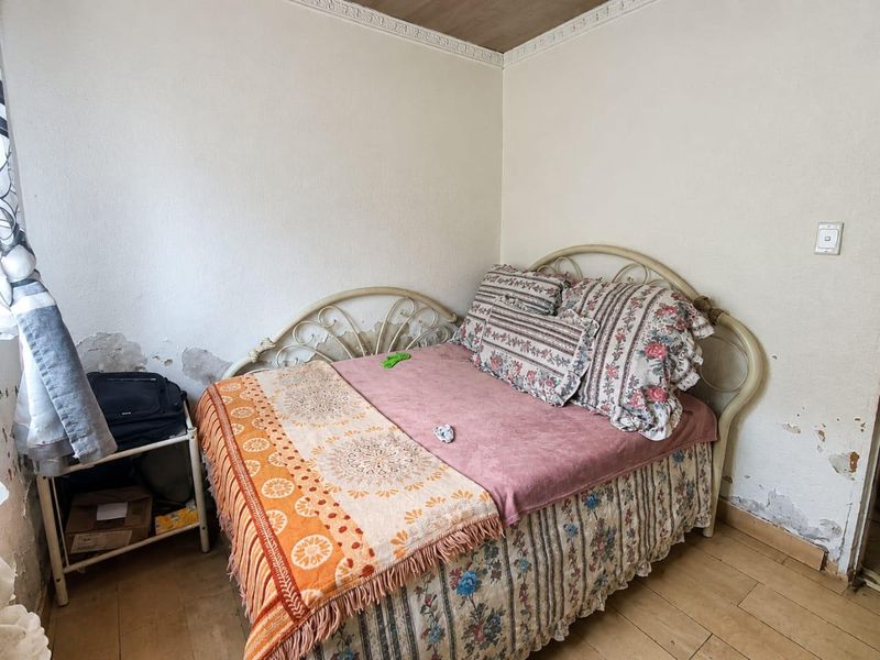 A bedroom featuring tiled flooring and crown molding, currently requiring wall repairs and cosmetic updates to improve the overall condition.