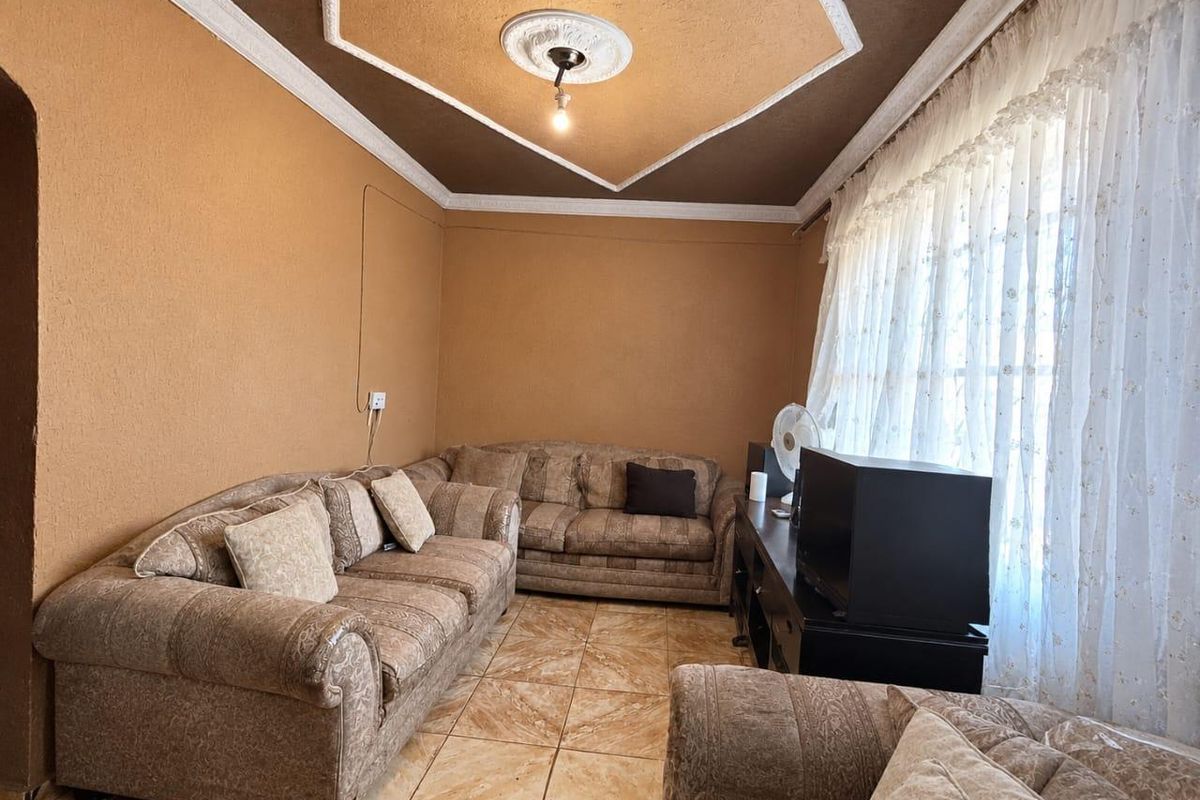 A living room featuring ceramic floor tiles, decorative ceiling coving, and a central ceiling rose.