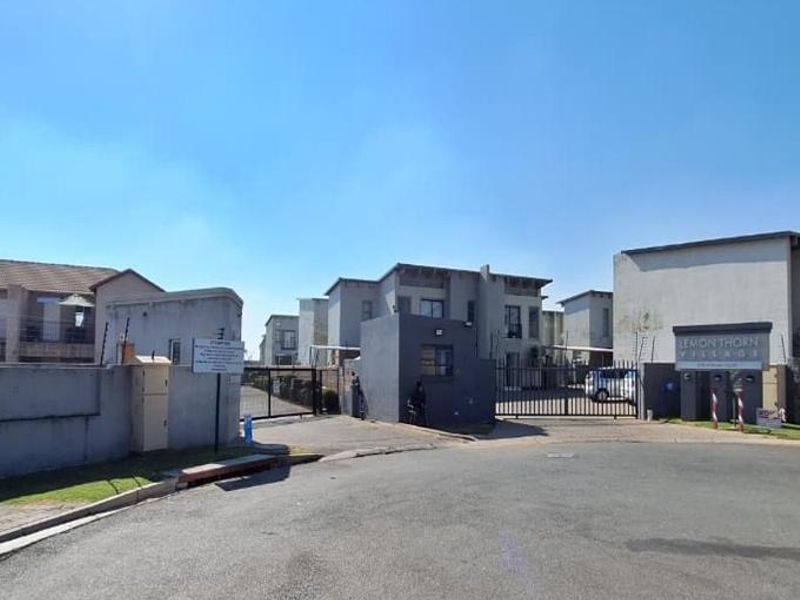 Street view of the entrance to Lemon Thorn Village, featuring a secure gated access point with perimeter walling and electric fencing.
