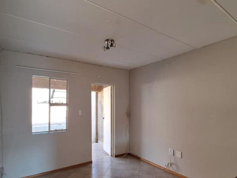 An empty living room featuring tiled flooring and a ceiling tile finish, offering a blank canvas for renovation and interior design.