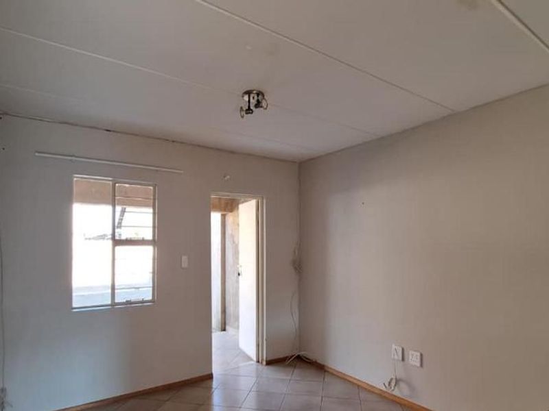 An empty living room featuring tiled flooring and neutral walls, offering a blank canvas for personalization and interior design updates.