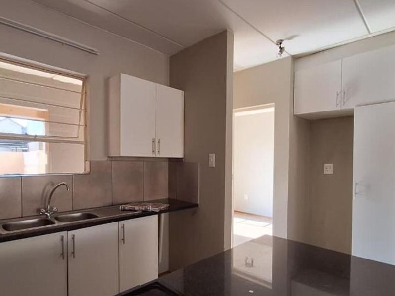 A functional kitchen featuring white cabinetry, dark countertops, a double sink, and a tiled backsplash, offering a clean and practical workspace.