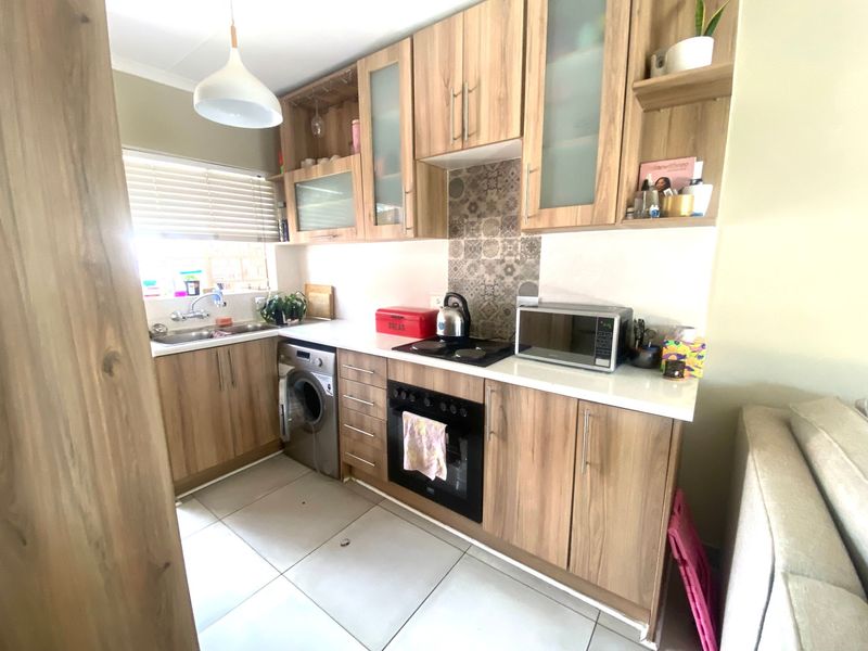 A functional kitchen featuring wood-look cabinetry, integrated appliances, tiled flooring, and a decorative backsplash, offering a clean and practical workspace.