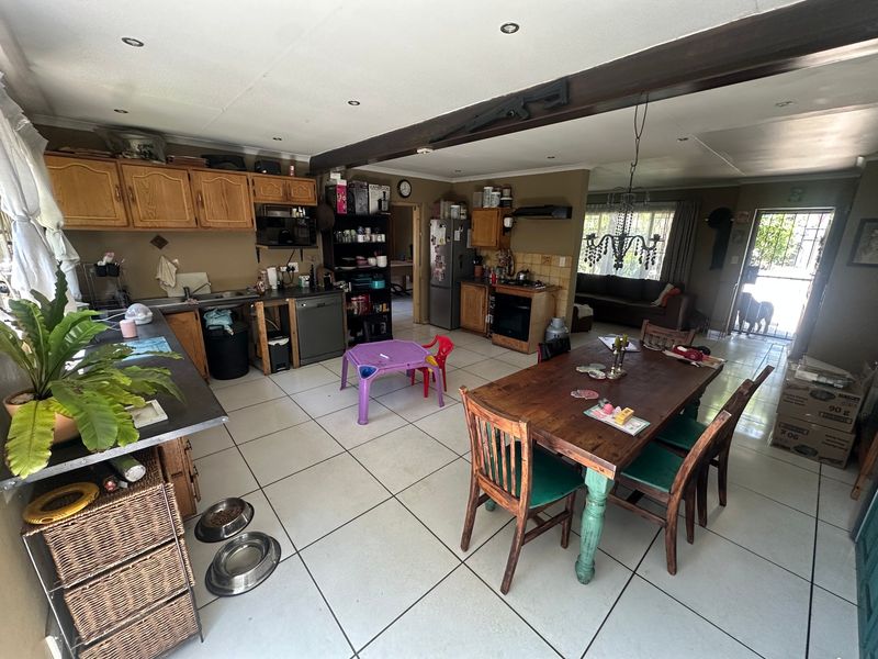 Spacious open-plan kitchen and dining area featuring tiled flooring, wooden cabinetry, and recessed lighting, offering a functional layout for family living.