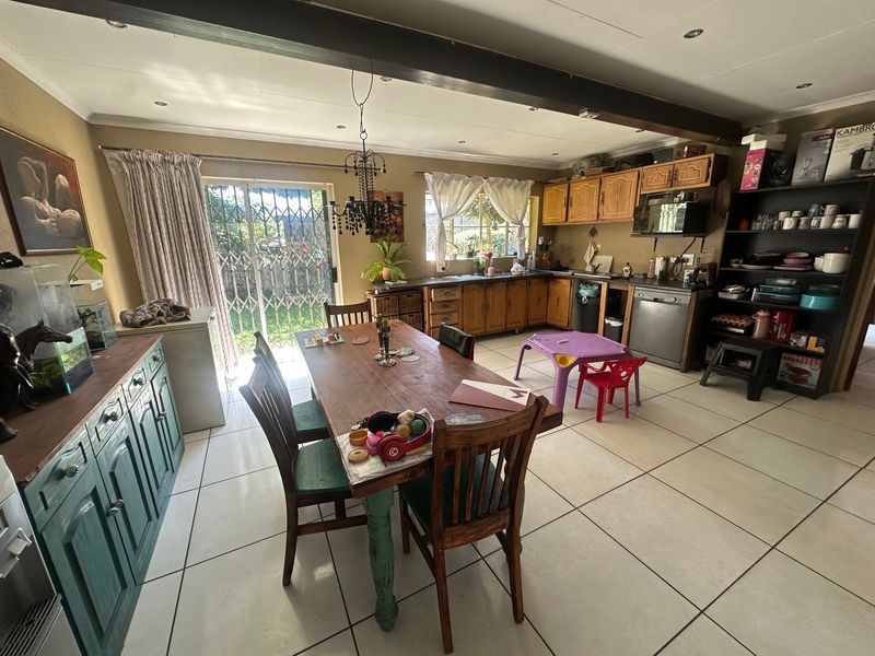 Open-plan kitchen and dining area featuring tiled floors, wooden cabinetry, and direct access to the garden through a sliding glass door.