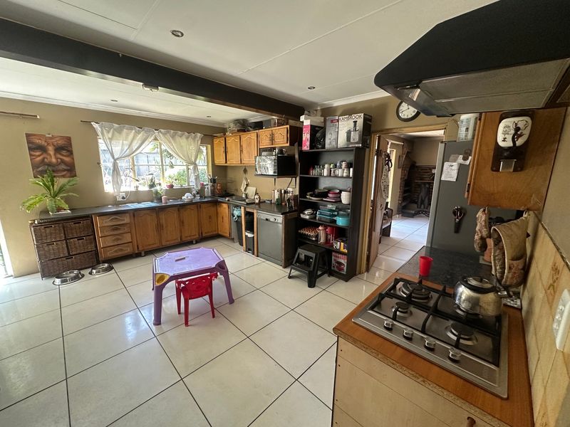Spacious kitchen featuring wooden cabinetry, gas hob, extractor fan, and tiled flooring, offering a functional layout with potential for modern updates.