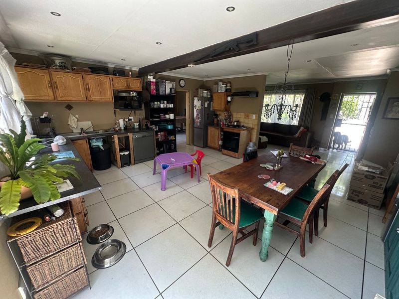 Open-plan kitchen and dining area featuring tiled flooring, wooden cabinetry, built-in oven, and recessed lighting, offering a functional layout for family living.